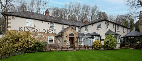 A Kings Lodge building with a stone facade, a wooden entrance, and a well-maintained lawn.