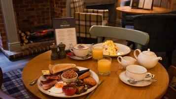 A breakfast table with a menu, a teapot, cups, and a glass of orange juice.