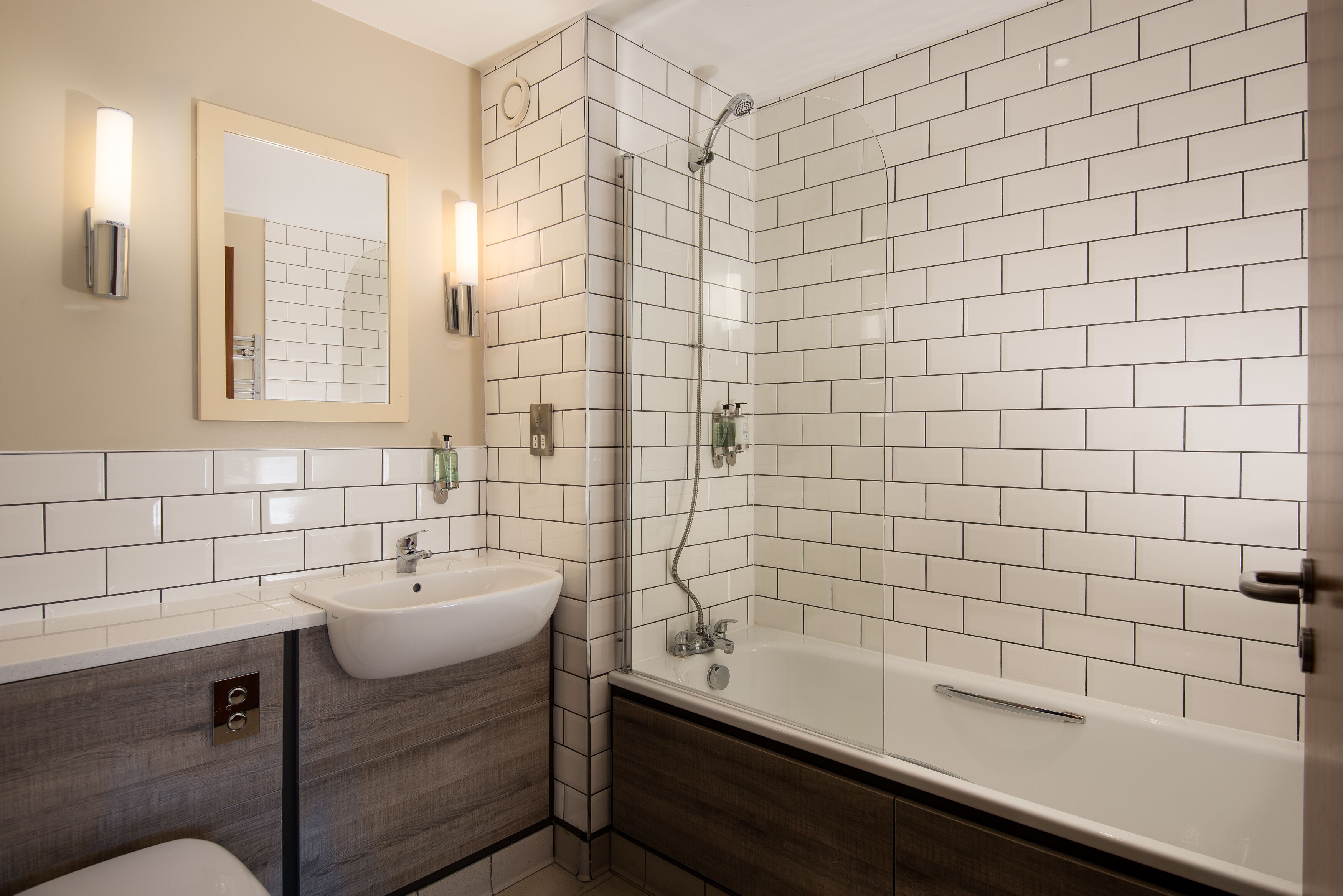 A bathroom with a white sink, mirror, and shower.