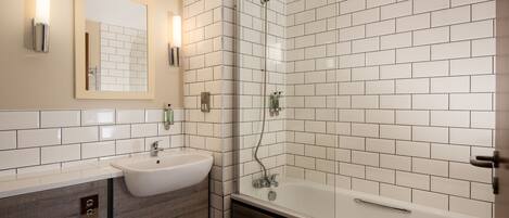 A bathroom with a white sink, mirror, and shower.