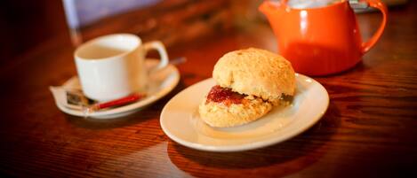 A table with a white cup, a red teapot, and a biscuit on a saucer.