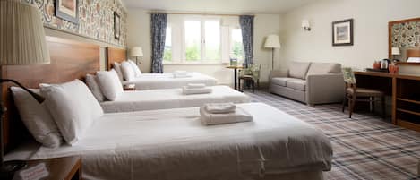A hotel room with two beds, a sofa, a desk, and a window with curtains.