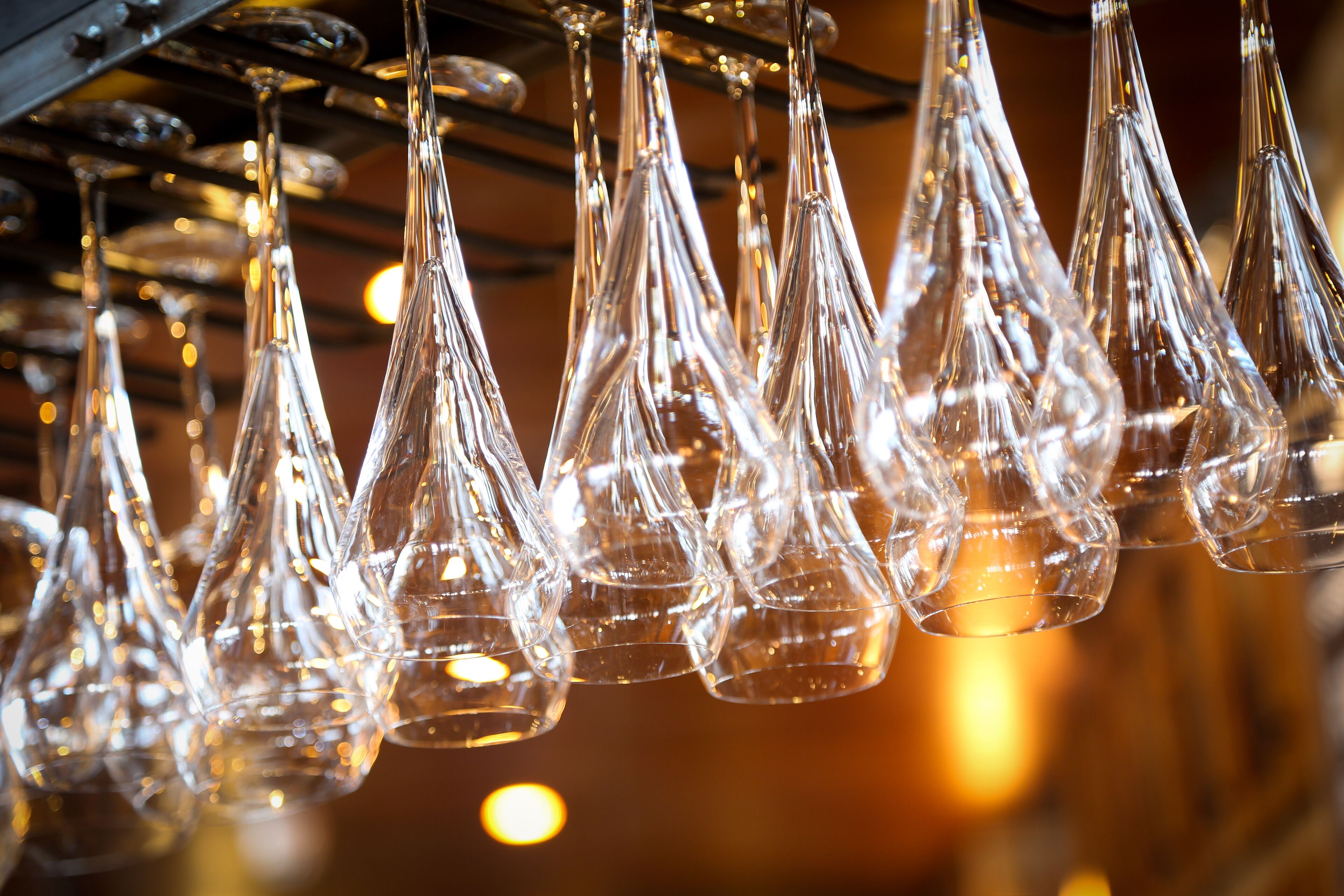 Varias copas de cristal transparente colgadas de una estructura metálica.