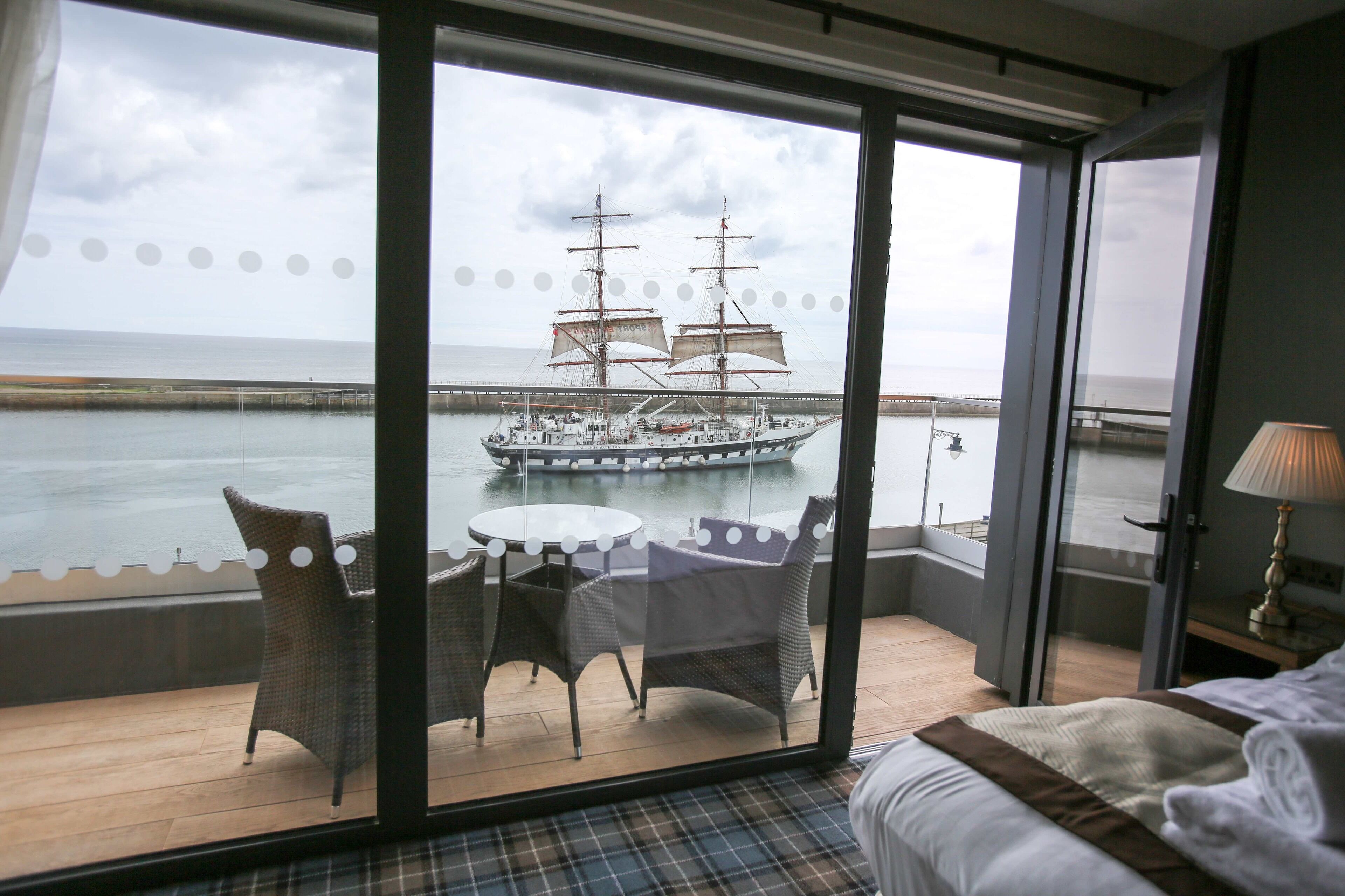 Quarto com uma grande janela que dá para a água, um navio e uma vista de uma ponte.
