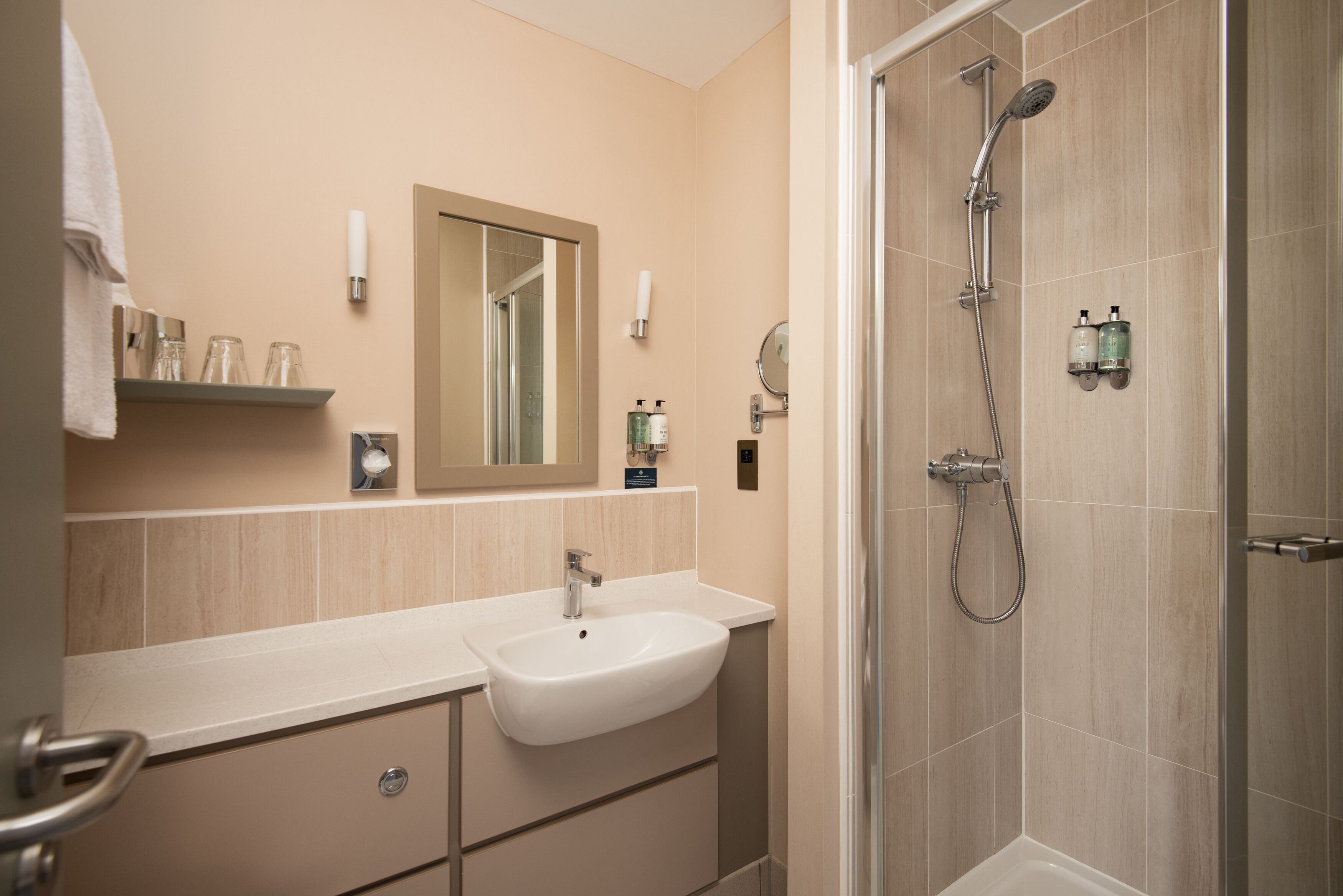 Un baño moderno con lavamanos, espejo y ducha.