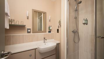 Un baño moderno con lavamanos, espejo y ducha.