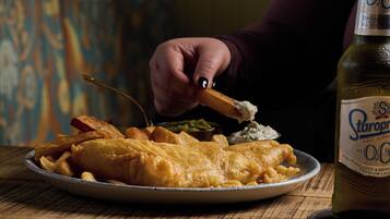Une assiette de poisson-frites accompagnée d’une bouteille de bière.