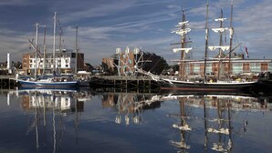 A harbor with two large sailing ships docked, surrounded by buildings and a clear sky. - The Commissioners Quay Inn - The Inn Collection Group (Blyth)