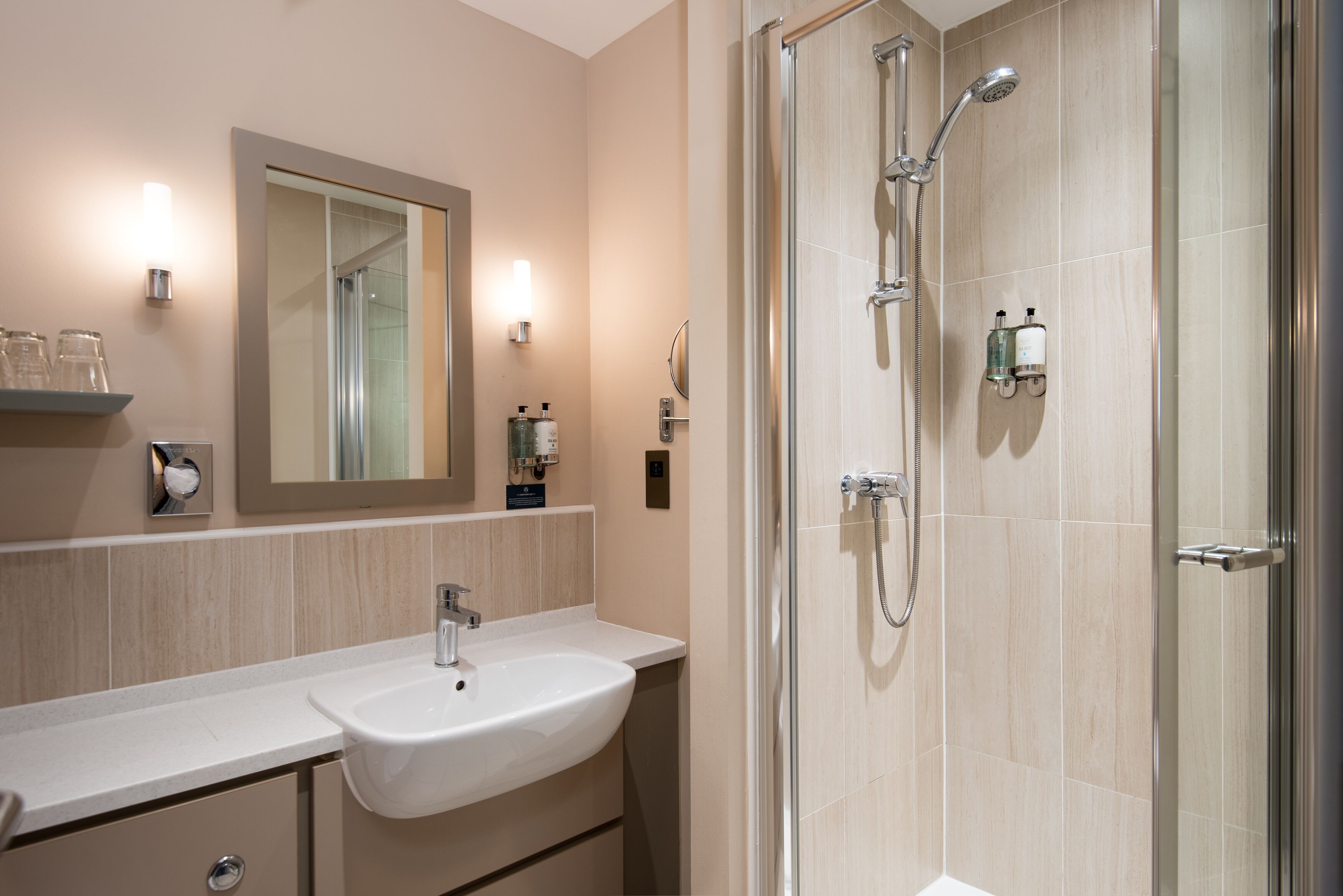 A modern bathroom with a sink, mirror, and glass-enclosed shower.