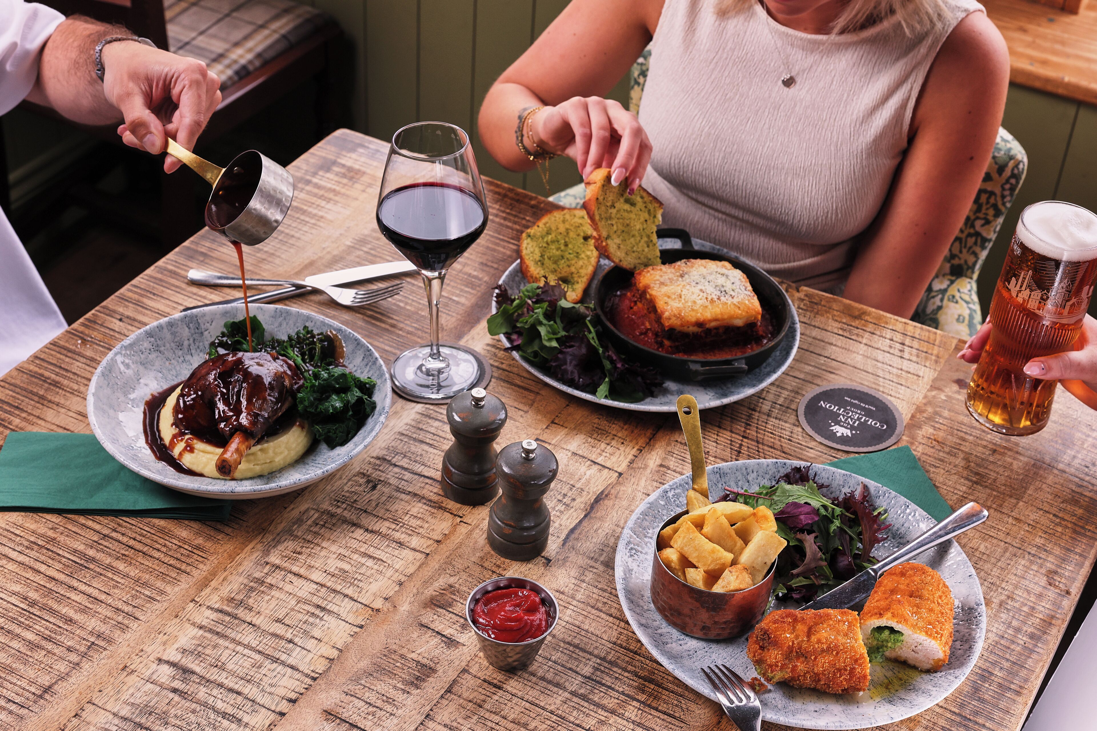 A dining table with various dishes, a wine glass, and a beer mug.