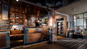 A cozy restaurant with a brick wall, wooden counter, and a sign indicating check-in/check-out. - The Commissioners Quay Inn - The Inn Collection Group (Blyth)