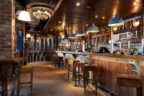 A bar area with wooden bar stools, hanging pendant lights, and a brick wall. - The Commissioners Quay Inn - The Inn Collection Group (Blyth)