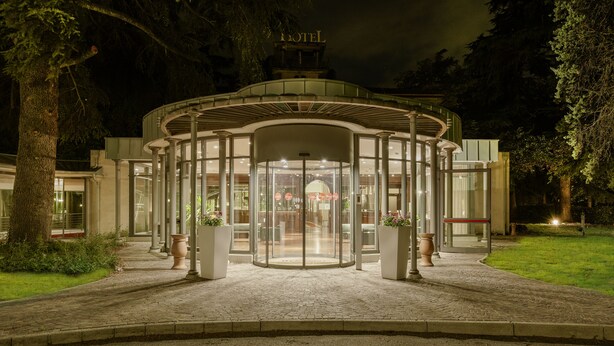 A hotel entrance with a glass revolving door, a central light fixture, and a sign above the door. - Meditur Hotel Bologna (San Lazzaro di Savena)