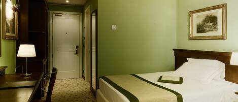 Habitación de hotel con cama, escritorio y silla. Se ve una puerta que da a otra habitación.