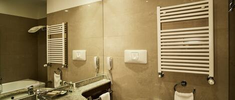 A modern bathroom with a granite sink, a toilet, and a bidet. There are two towel racks, a mirror, and a wall-mounted phone.