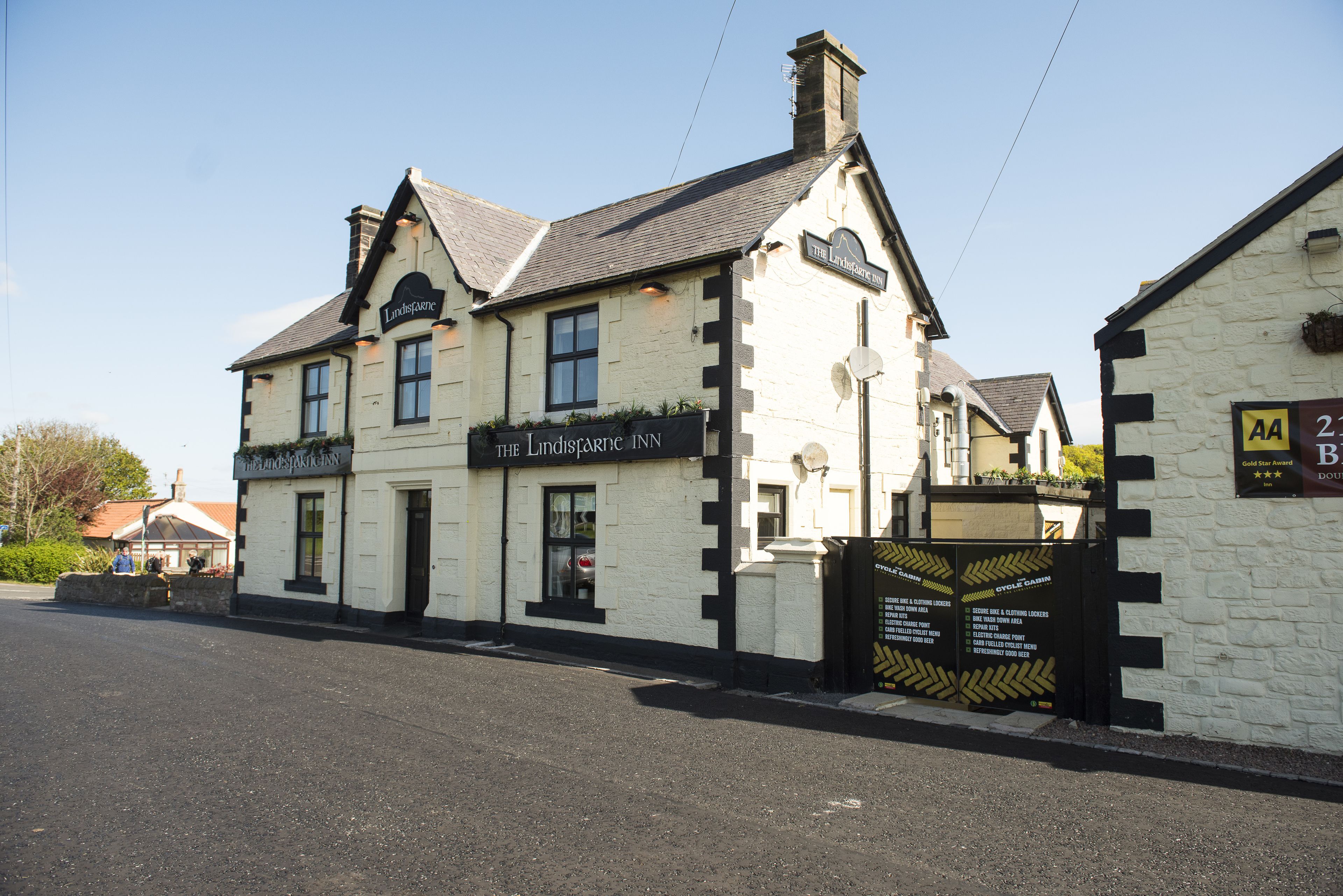 Un edificio tradicional con un cartel que indica 'The Lindisfarne Inn' y una paleta de colores blanco y negro.