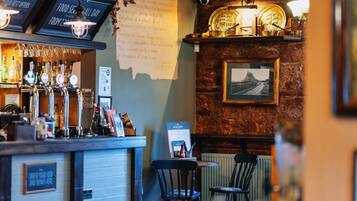 Un espace bar avec un mur en pierre, un tableau encadré et un panneau affichant le menu.