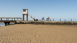 Une plage de sable avec une promenade en bois et un poste de surveillance pour les sauveteurs.