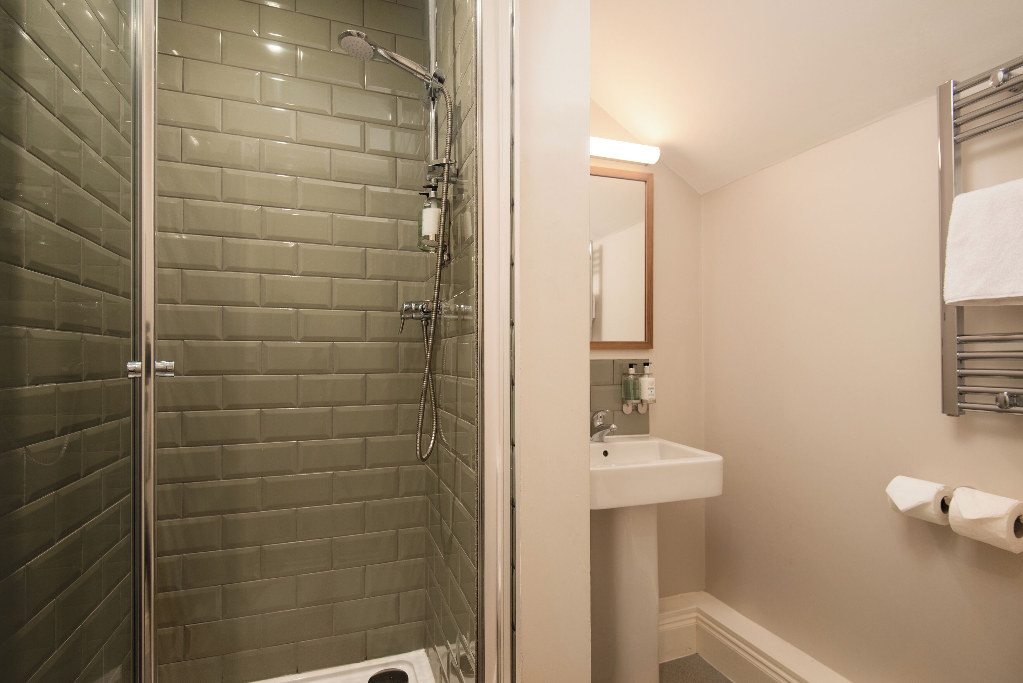 A bathroom with a glass-enclosed shower, a sink, and a mirror.