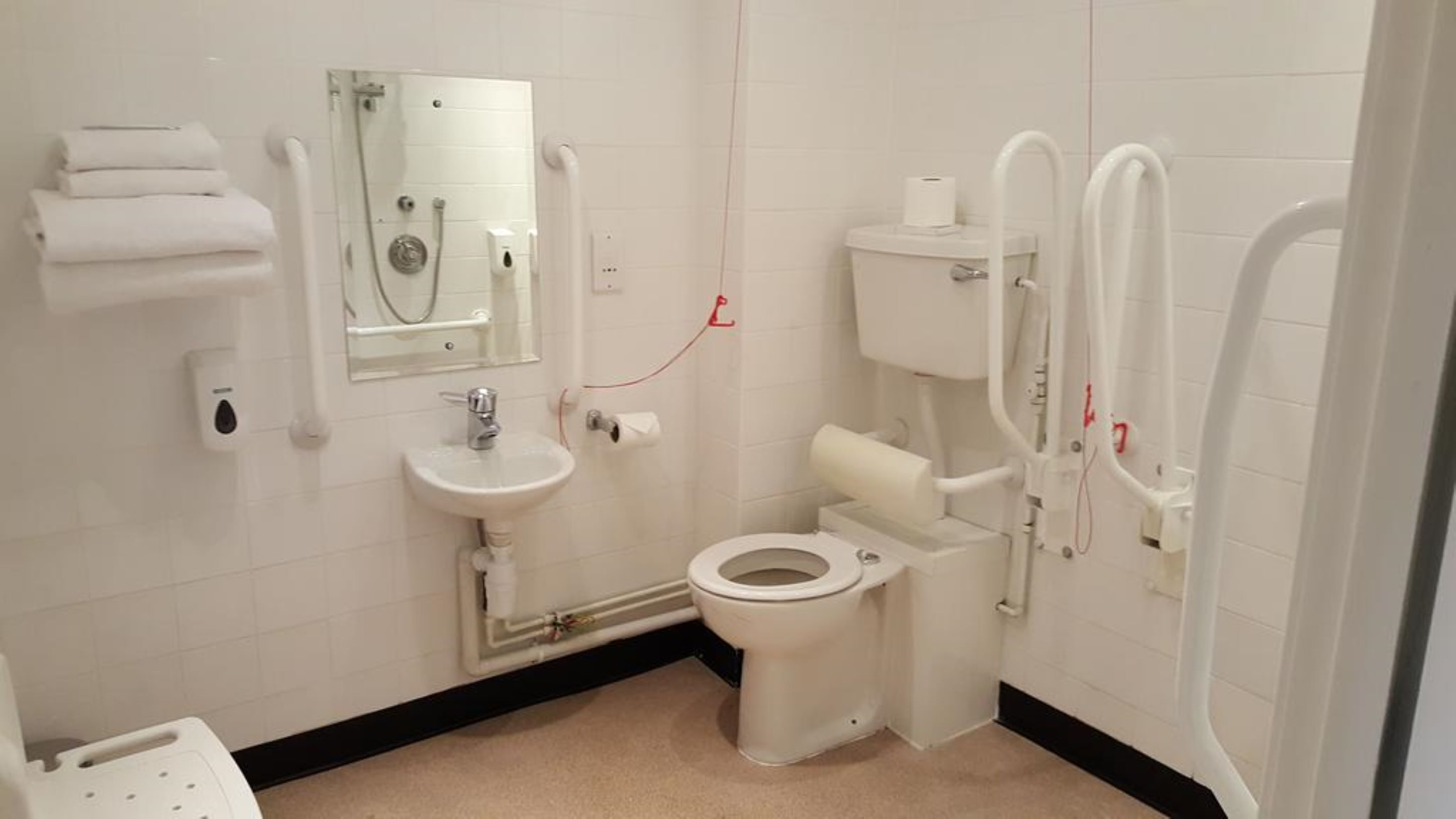 A small, clean bathroom with a toilet, sink, and hand dryer.