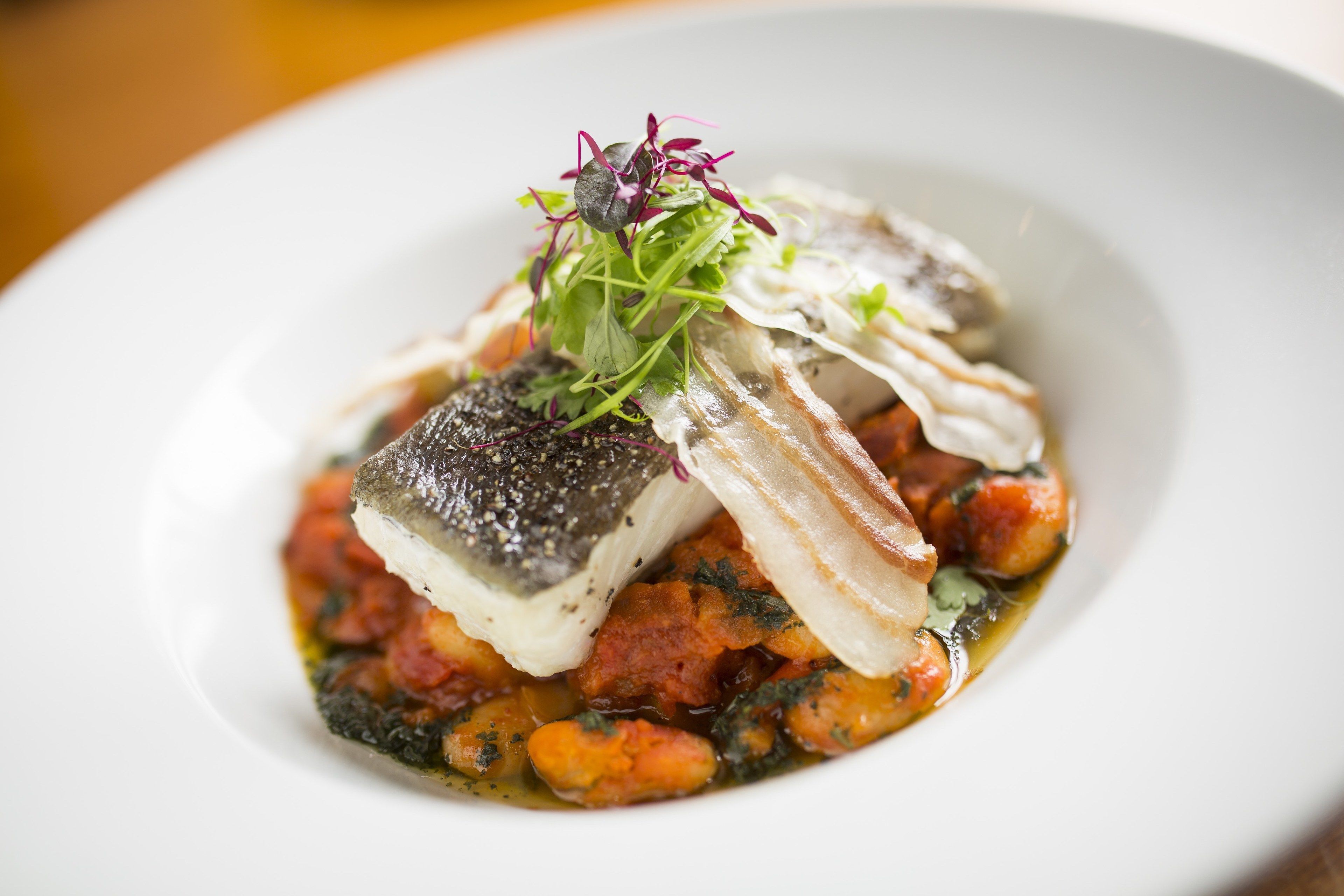 A plate of food with fish, vegetables, and a garnish.