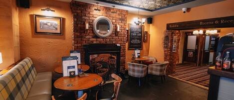 A cozy restaurant with a brick wall, a fireplace, and a seating area with tables and chairs.