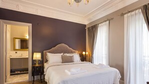Un dormitorio con una cama grande, una mesita de noche, una lámpara, un espejo y vistas al baño.