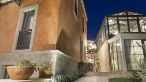 Un edificio con fachada de piedra, una conservatorio de vidrio y una entrada bien iluminada.