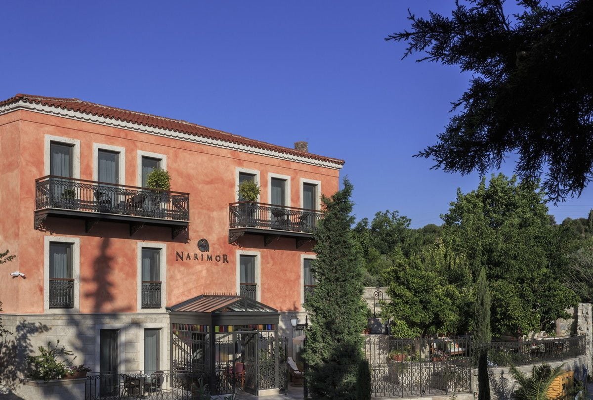 A two-story building with balconies, a sign reading "NARIMOR," and a gated entrance.