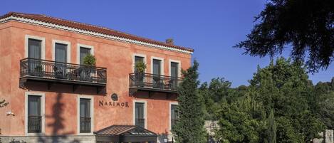A two-story building with balconies, a sign reading "NARIMOR," and a gated entrance.