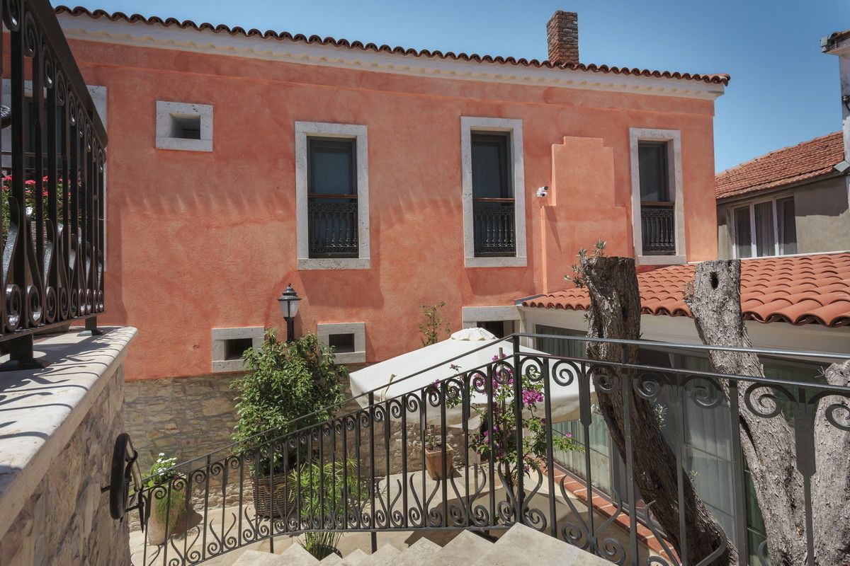 A building with a pink facade, a stone staircase, and a metal railing.
