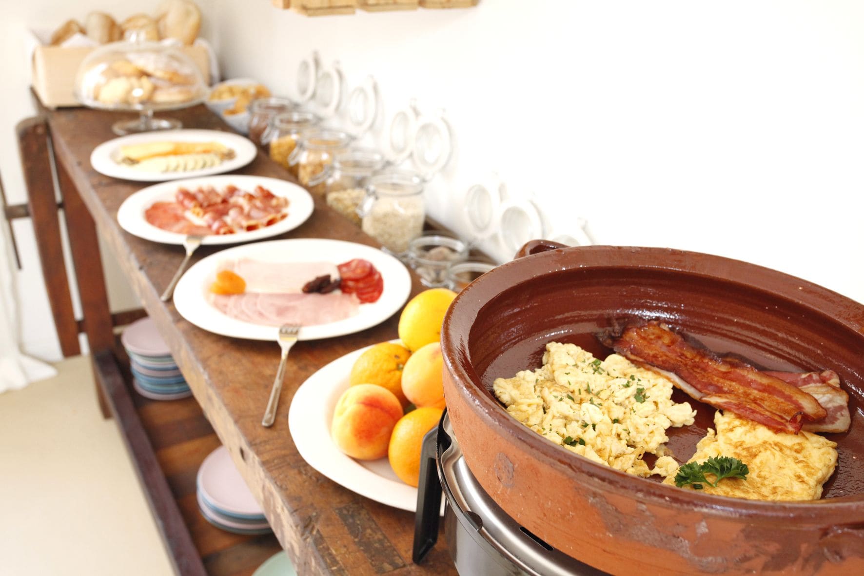 A breakfast buffet with various dishes including eggs, bacon, and pastries.