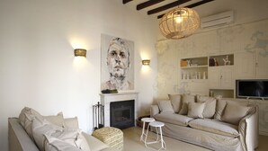 Ein Wohnzimmer mit Kamin, einer Couch, einem Fernseher und einem Bild an der Wand.