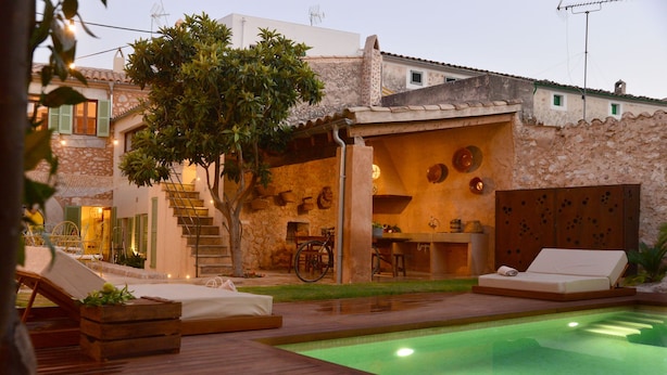 Ein Poolbereich mit Liegestühlen, Essbereich und einer Treppe zu einer überdachten Terrasse.