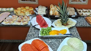 Un buffet proposant une variété d’aliments, notamment du pain, des sandwichs et des fruits.
