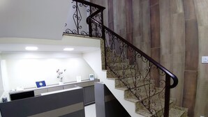 Une cuisine moderne dotée d’un îlot central intégré, d’un escalier avec des rampes en métal décoratives et d’un sol carrelé aux lignes épurées.