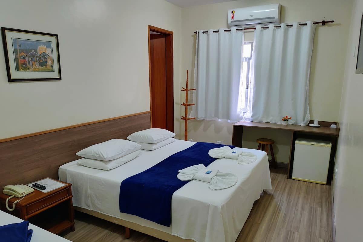Ein Hotelzimmer mit Bett, Nachttisch und Schreibtisch mit Stuhl.