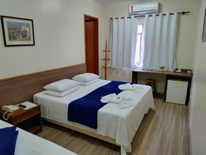 Una camera d'albergo con un letto, un comodino e una scrivania con una sedia.