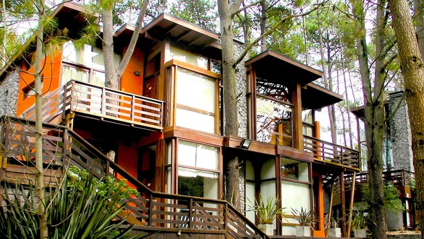 A multi-story wooden building with a staircase leading to the upper levels. - Altos Medanos - Cabañas y Club de Bosque (Mar de Las Pampas)