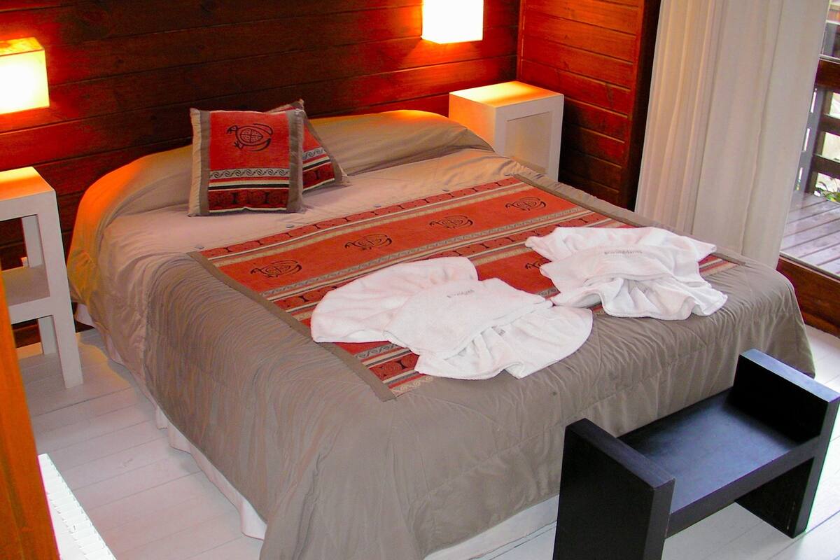 A neatly made bed with a patterned bedspread, pillows, and a bedside table with a lamp.