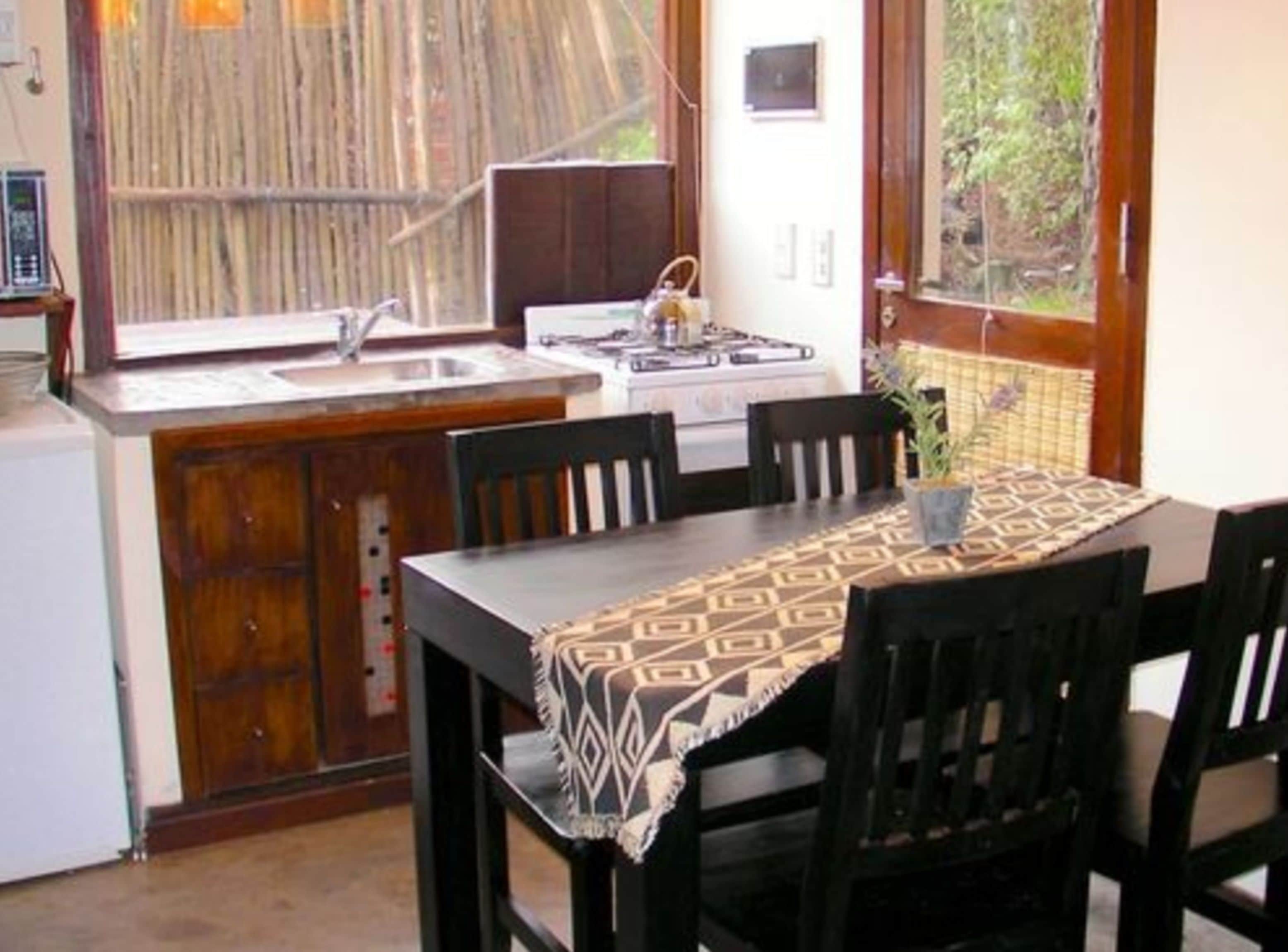 A kitchen with a dining table, chairs, a stove, and a sink.