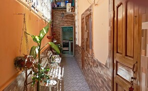 Stroll through this charming corridor to a well-equipped kitchen with a stove, cabinets, and sink.