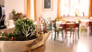 Un coin repas avec une table et des chaises en bois, une plante en pot et un tableau encadré au mur.