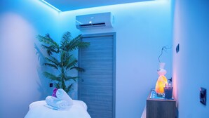 Une chambre d’hôtel moderne, équipée d’un lit, d’une plante en pot, d’un climatiseur et d’une table de chevet avec une lampe.