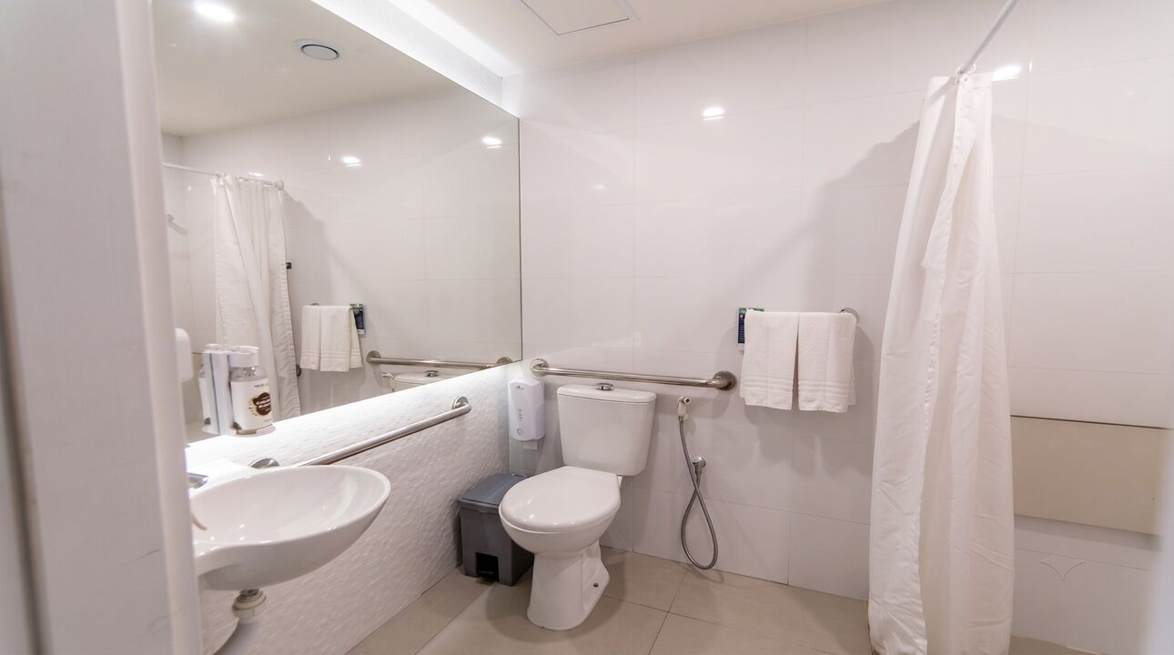 Un baño moderno con lavamanos, inodoro y cortina de ducha blancos.