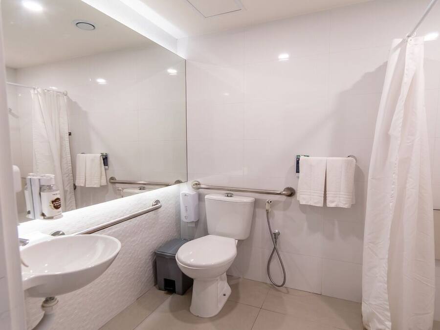 A modern bathroom with a white sink, toilet, and shower curtain.