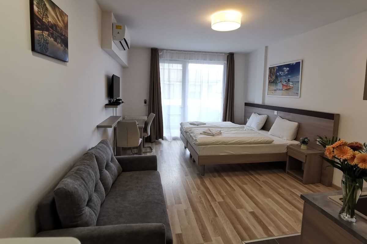 Een hotelkamer met een bed, een slaapbank, een bureau en een televisie.