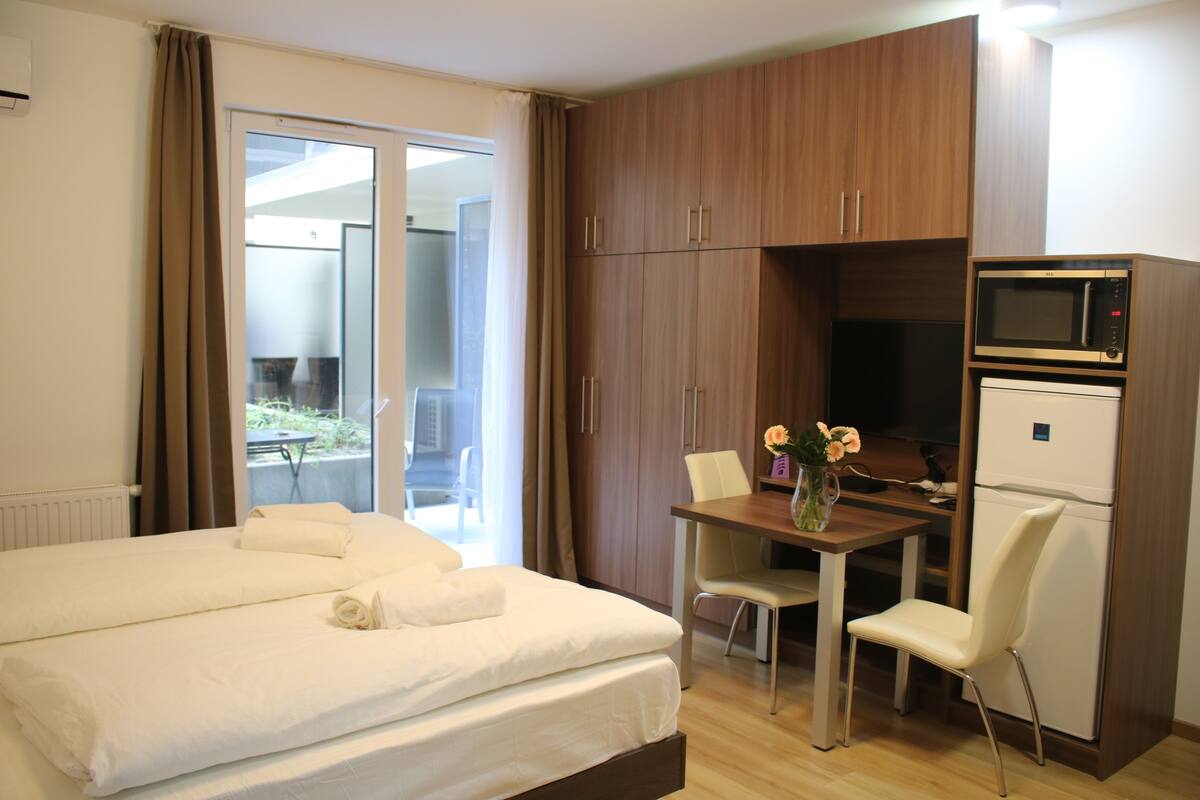 Een hotelkamer met een bed, een tafel met stoelen, een magnetron en een koelkast.