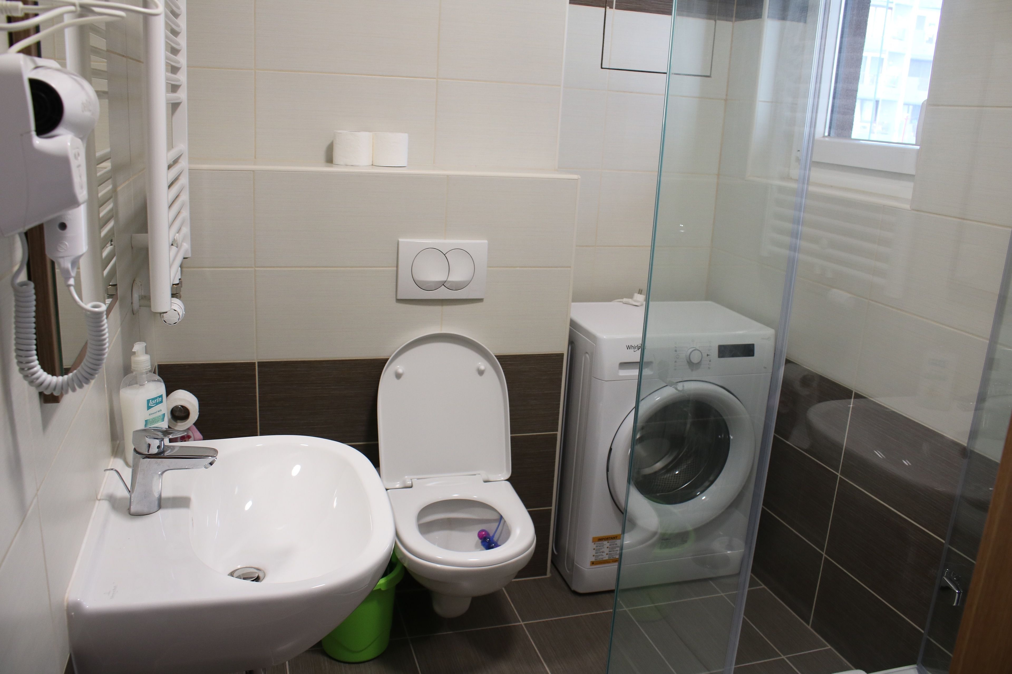 A bathroom with a sink, toilet, and washing machine.