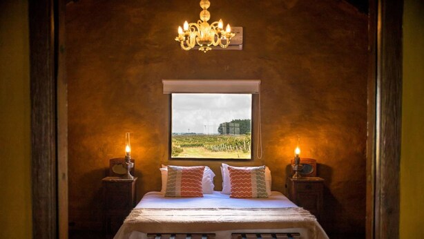 A cozy bedroom with a large window, a chandelier, and two bedside tables with candles.